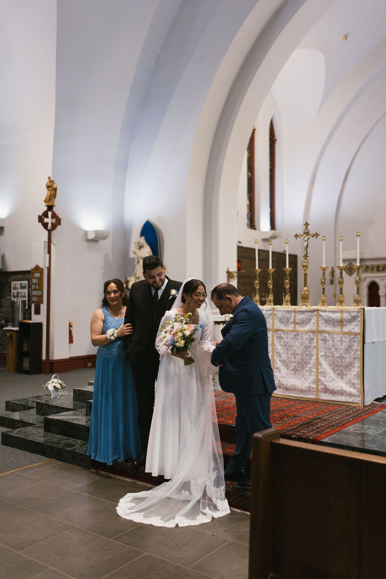 Bride and groom stand at church altar with wedding party during ceremony.