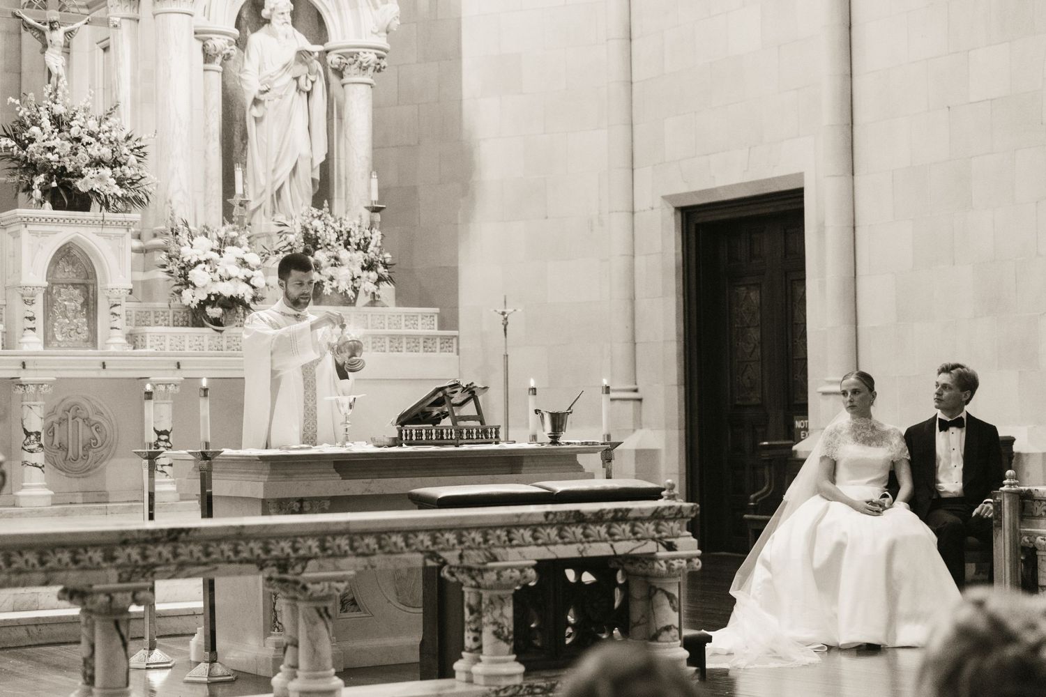 Black and white photo of a bride and groom at a church altar during a traditional wedding ceremony.