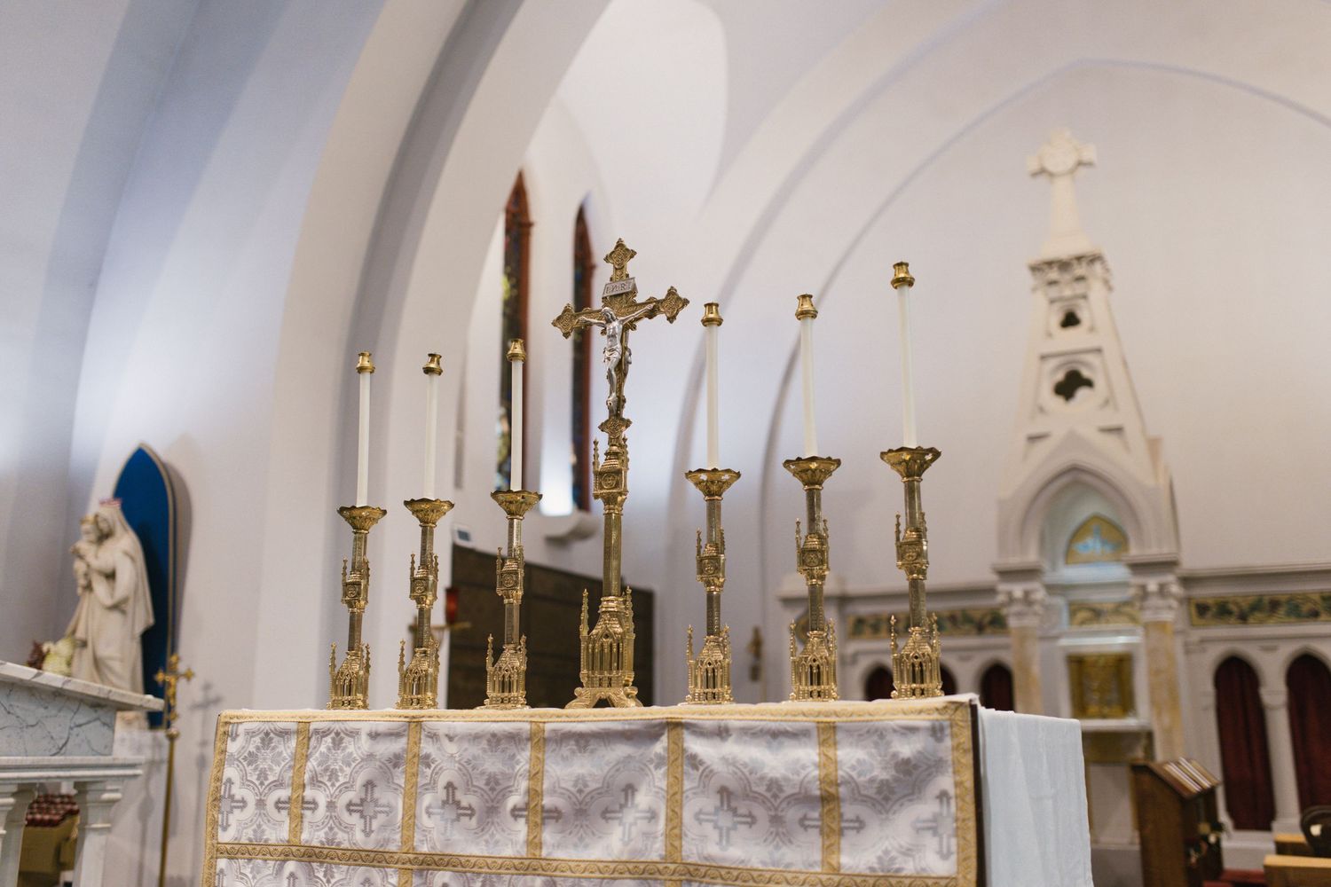 Ornate golden altar with candelabras and crucifix inside a classic Catholic church.