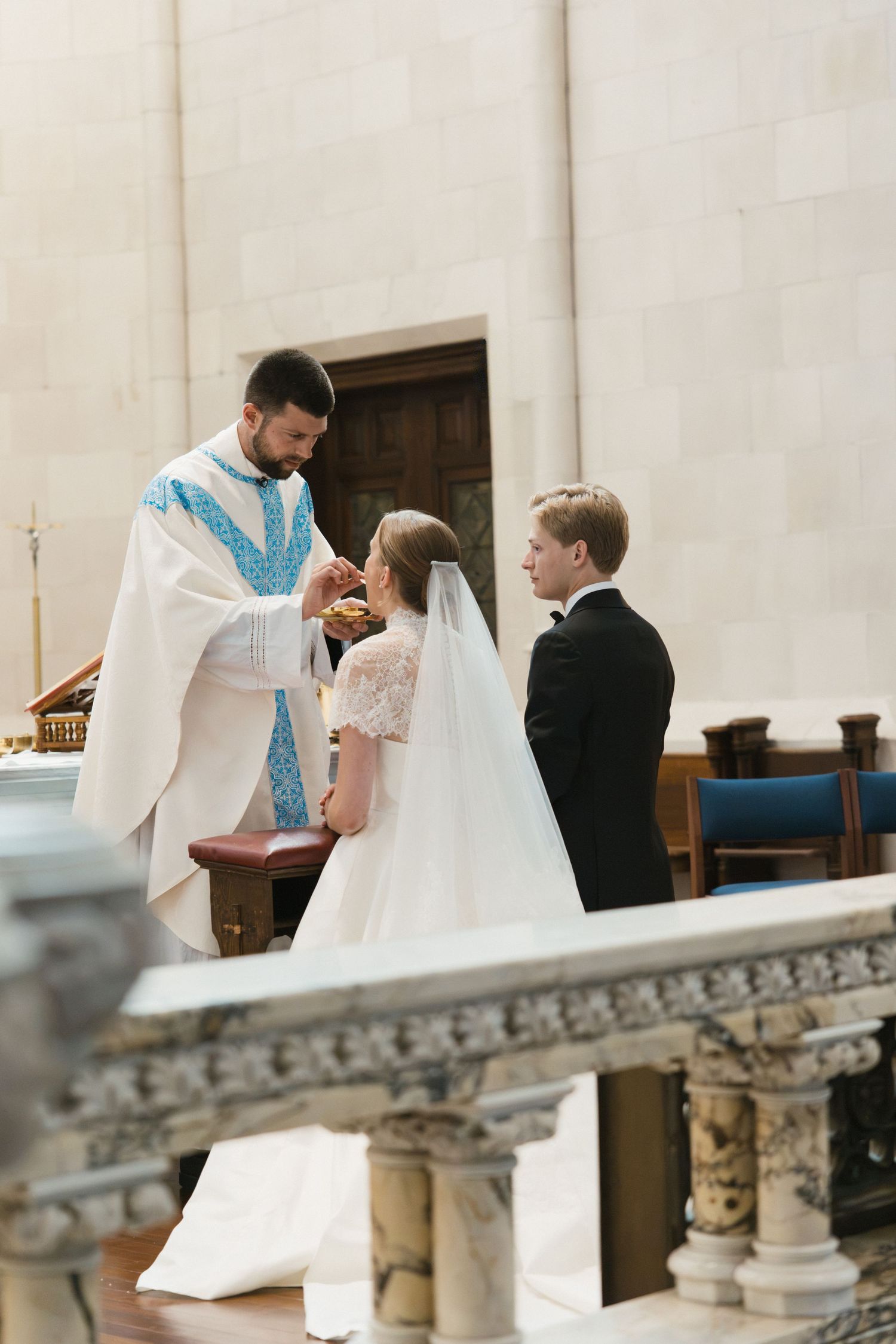 Priest officiating wedding ceremony, blessing bride and groom at the church altar during Catholic nuptials.