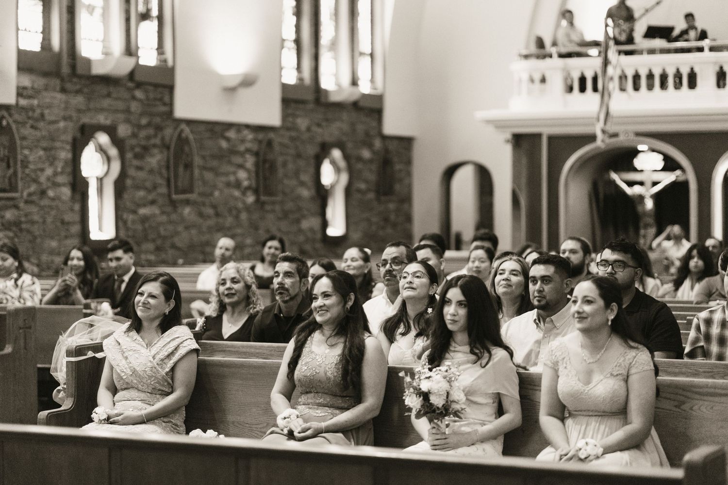 Wedding guests and bridesmaids in teal dresses seated in church pews during ceremony.