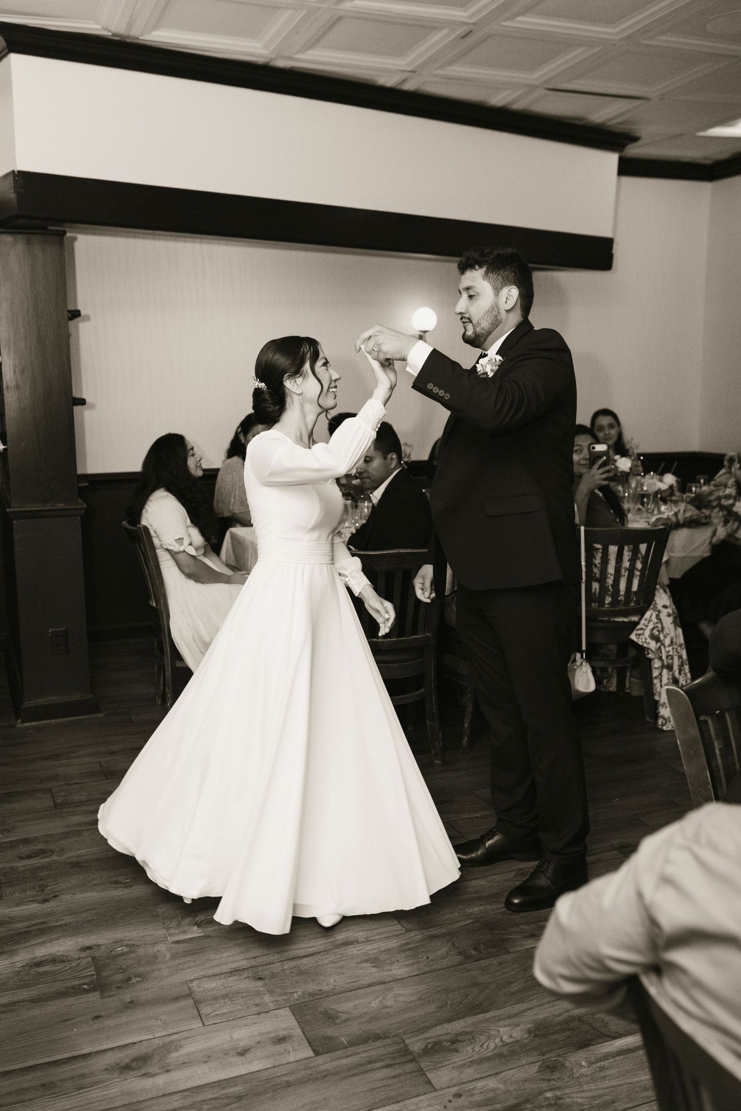 Black and white photo of bride and groom sharing first dance at wedding reception.