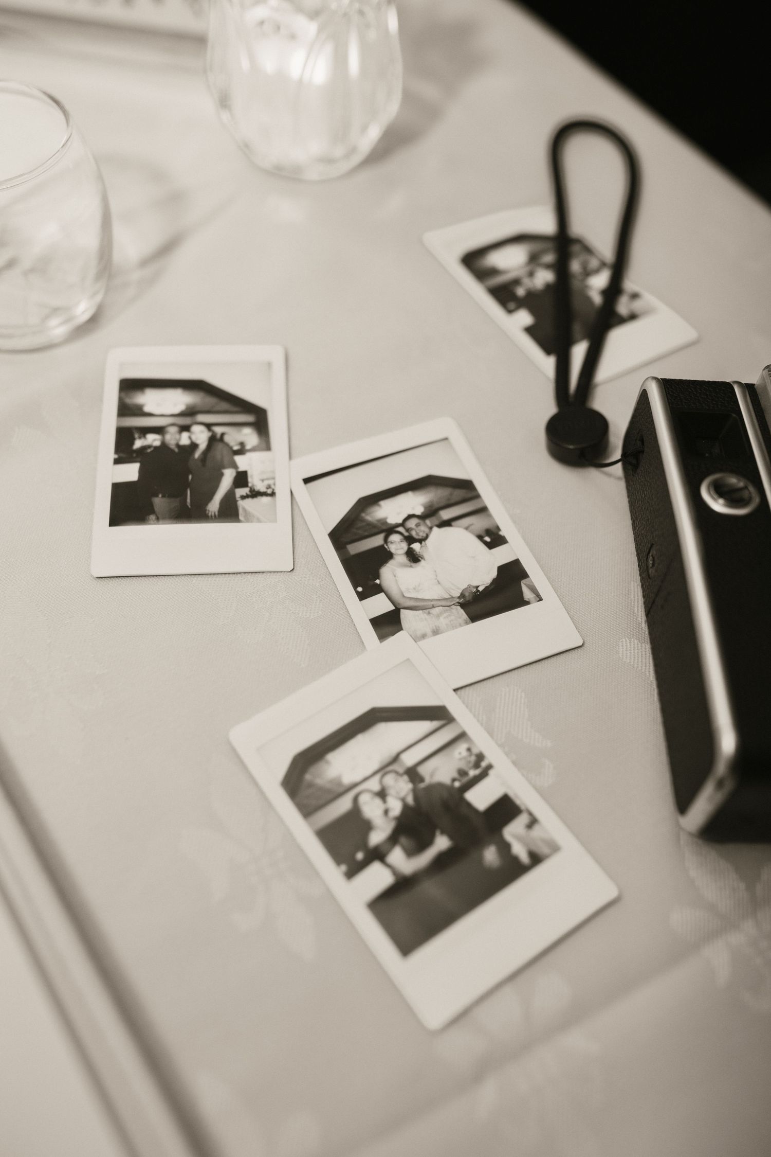 Black and white Instax polaroid photos of wedding couple displayed on reception table.