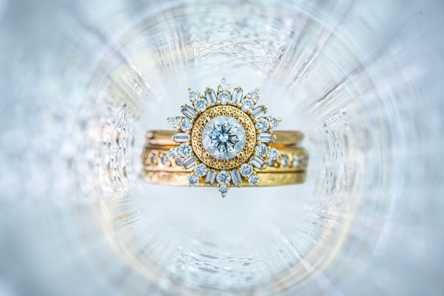Ornate vintage diamond and gold sunburst wedding ring displayed in crystal glass bowl.