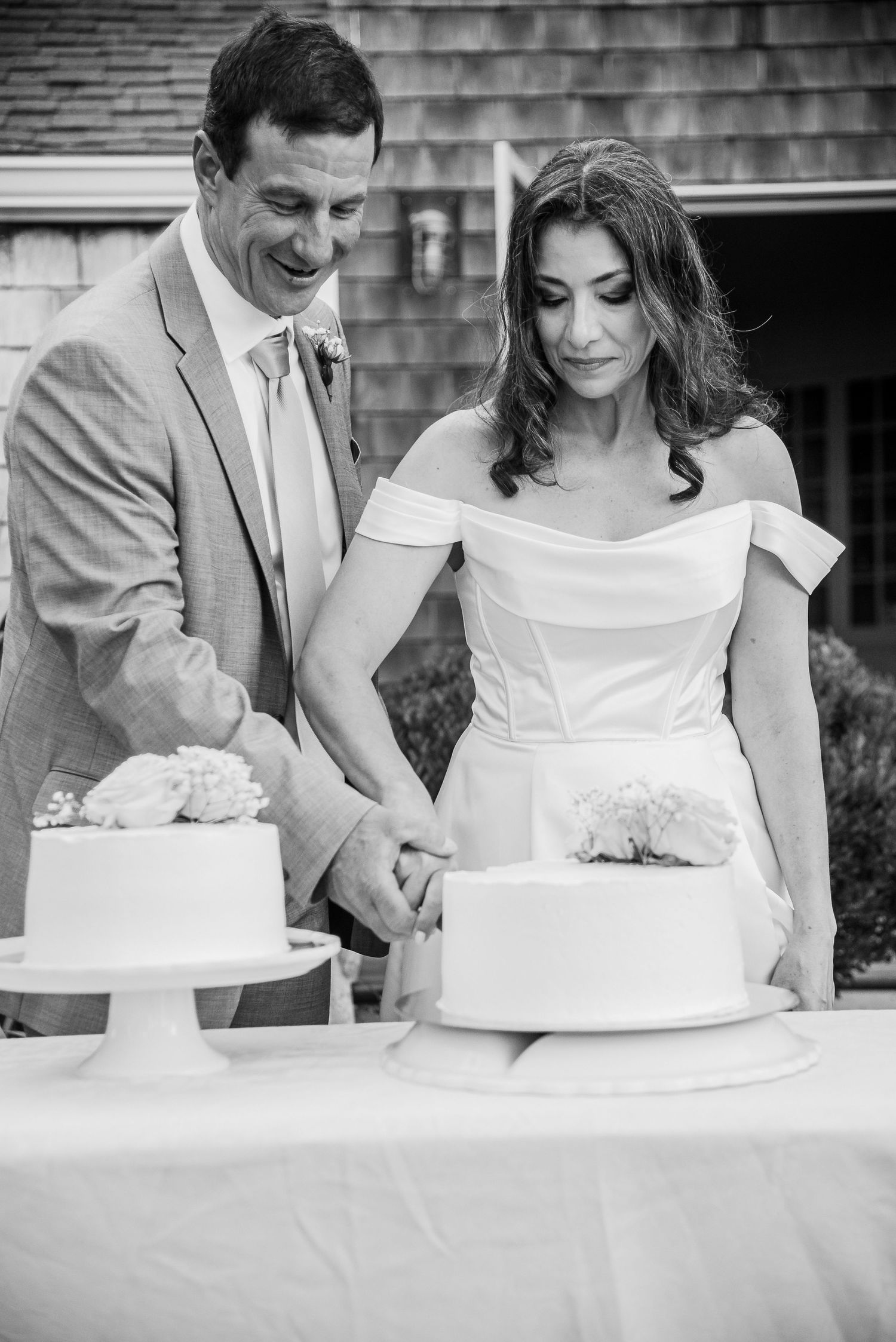 Bride and groom cutting wedding cake outdoors in elegant black and white wedding photo.