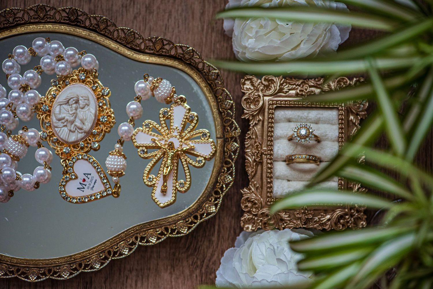 Elegant bridal jewelry flat lay with pearl rosary, gold brooch, and diamond ring on tray.