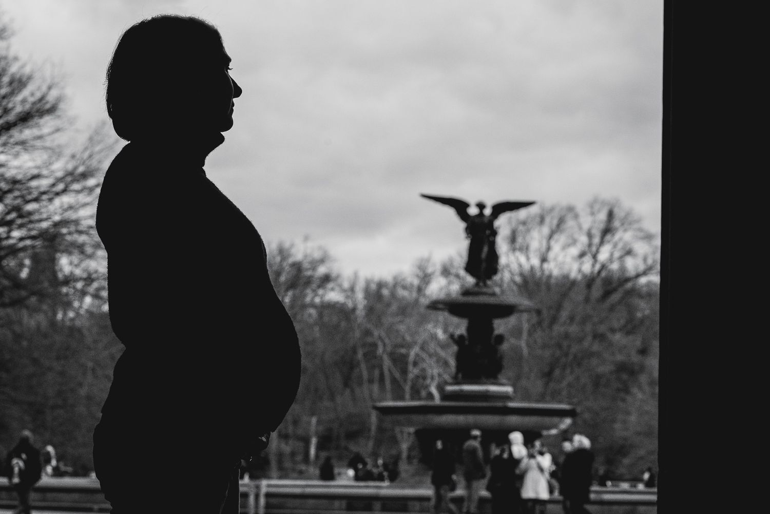 Silhouette of a pregnant woman standing near Bethesda Fountain in Central Park, New York City, black and white photo.