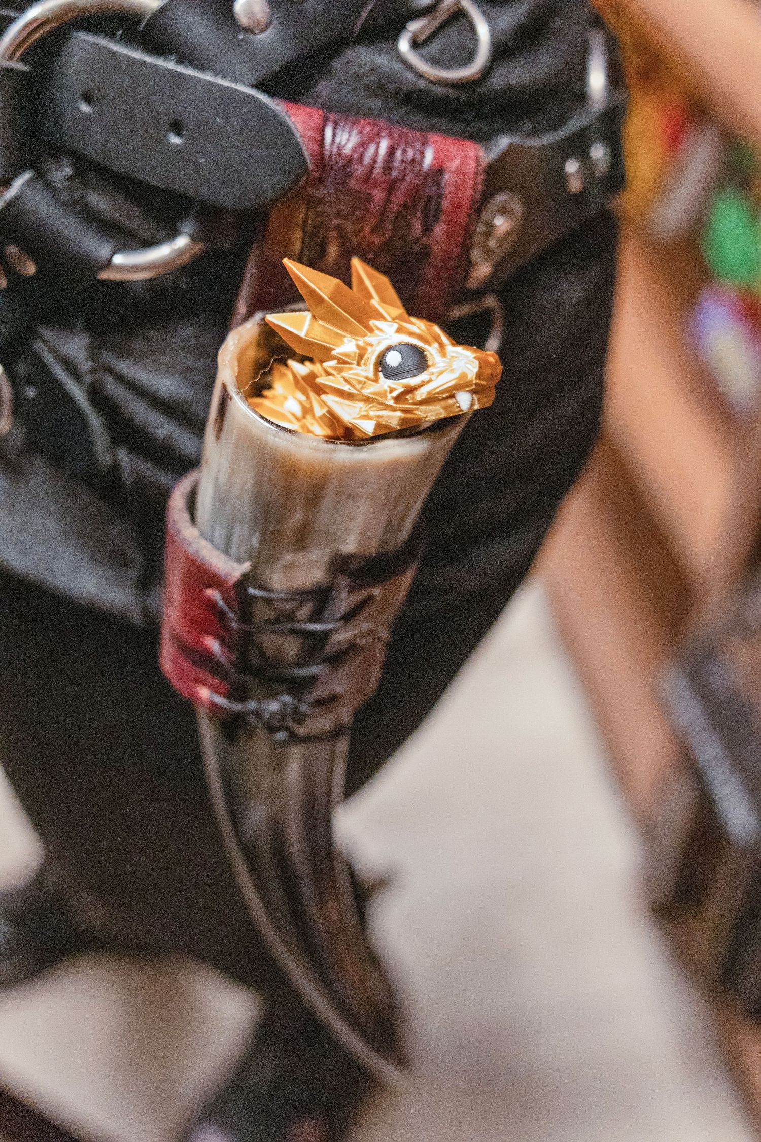 Gold dragon figurine peeking out of a leather-wrapped horn holster on a fantasy costume belt.