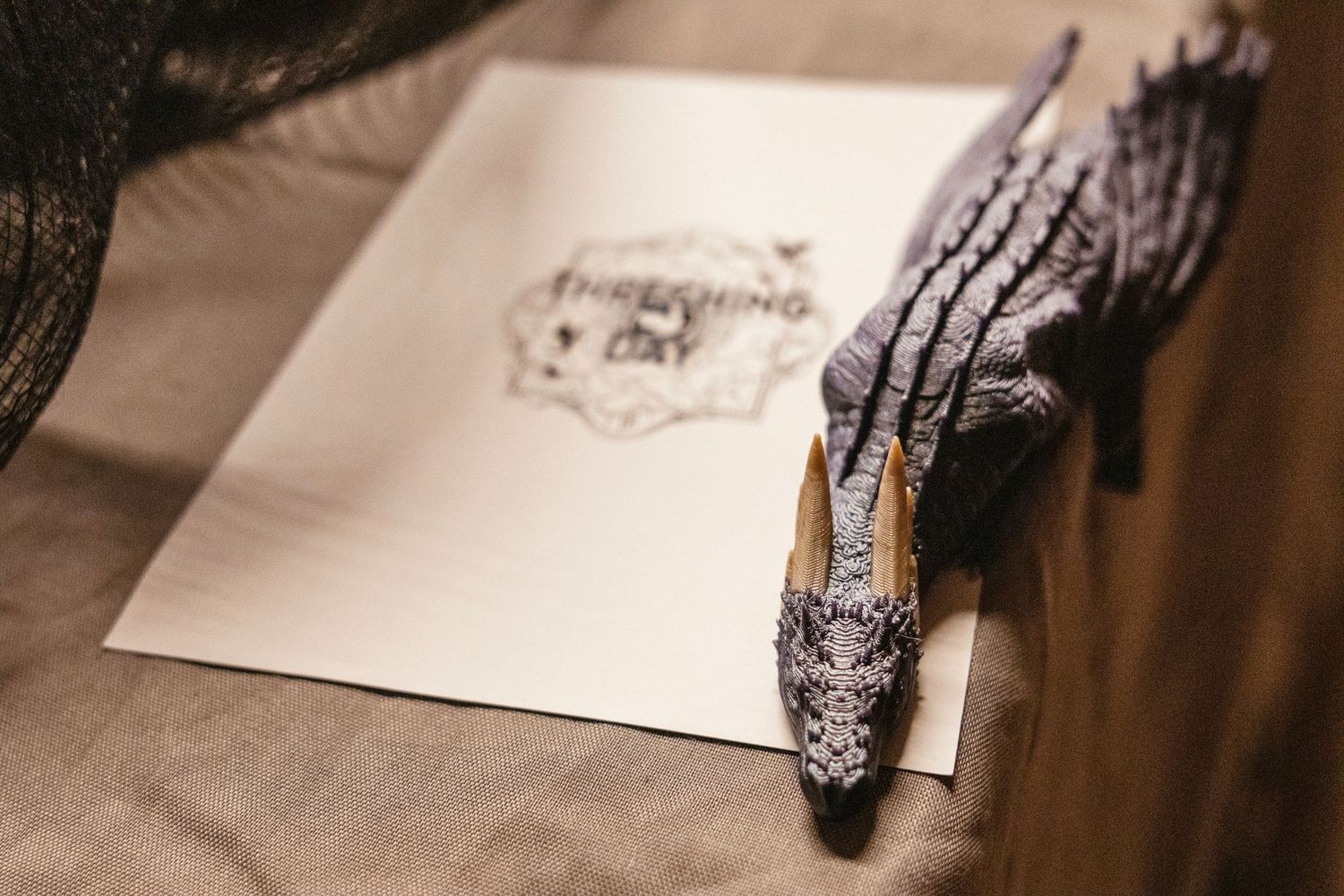 Elegant lace wedding shoe resting on an invitation card with decorative gloves on a neutral fabric background.