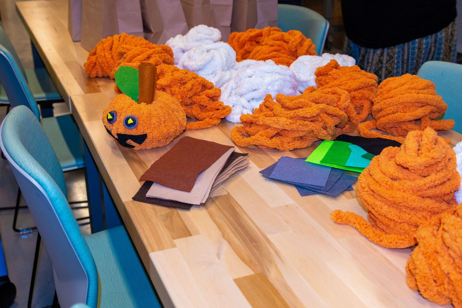 Orange yarn crafts and books displayed on a wooden table in a creative workshop setting.