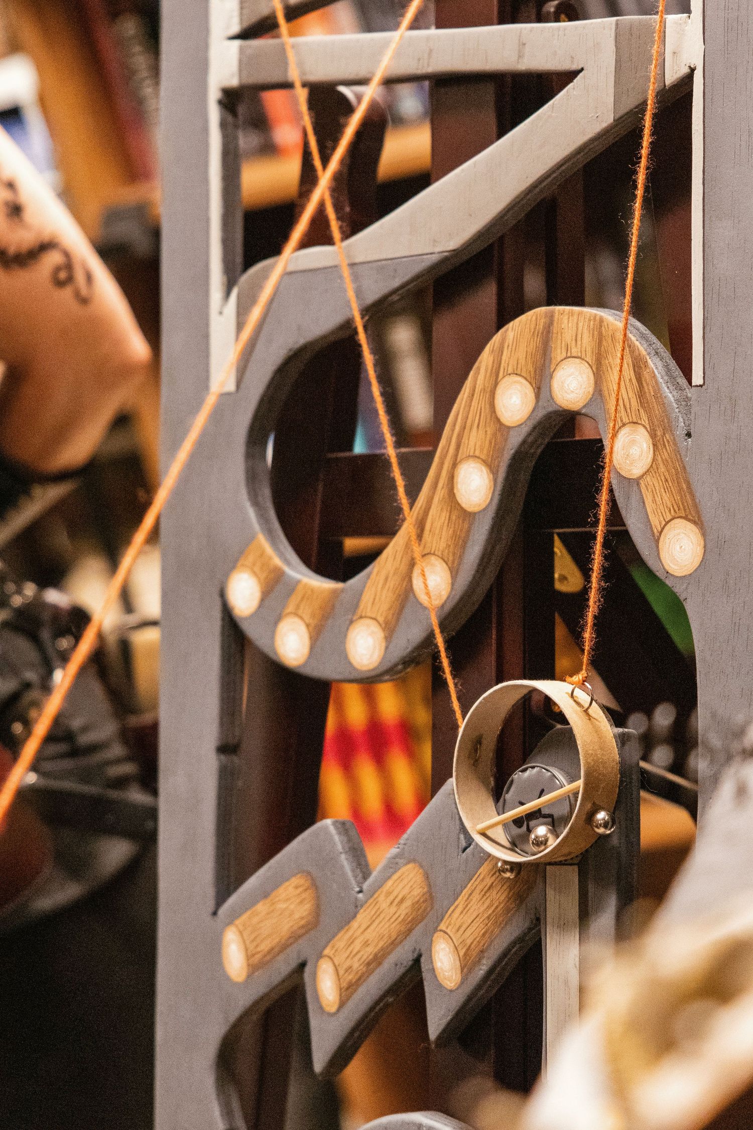 Handcrafted wooden snake-shaped pendants with inlaid dots hanging on orange cord at a craft fair.