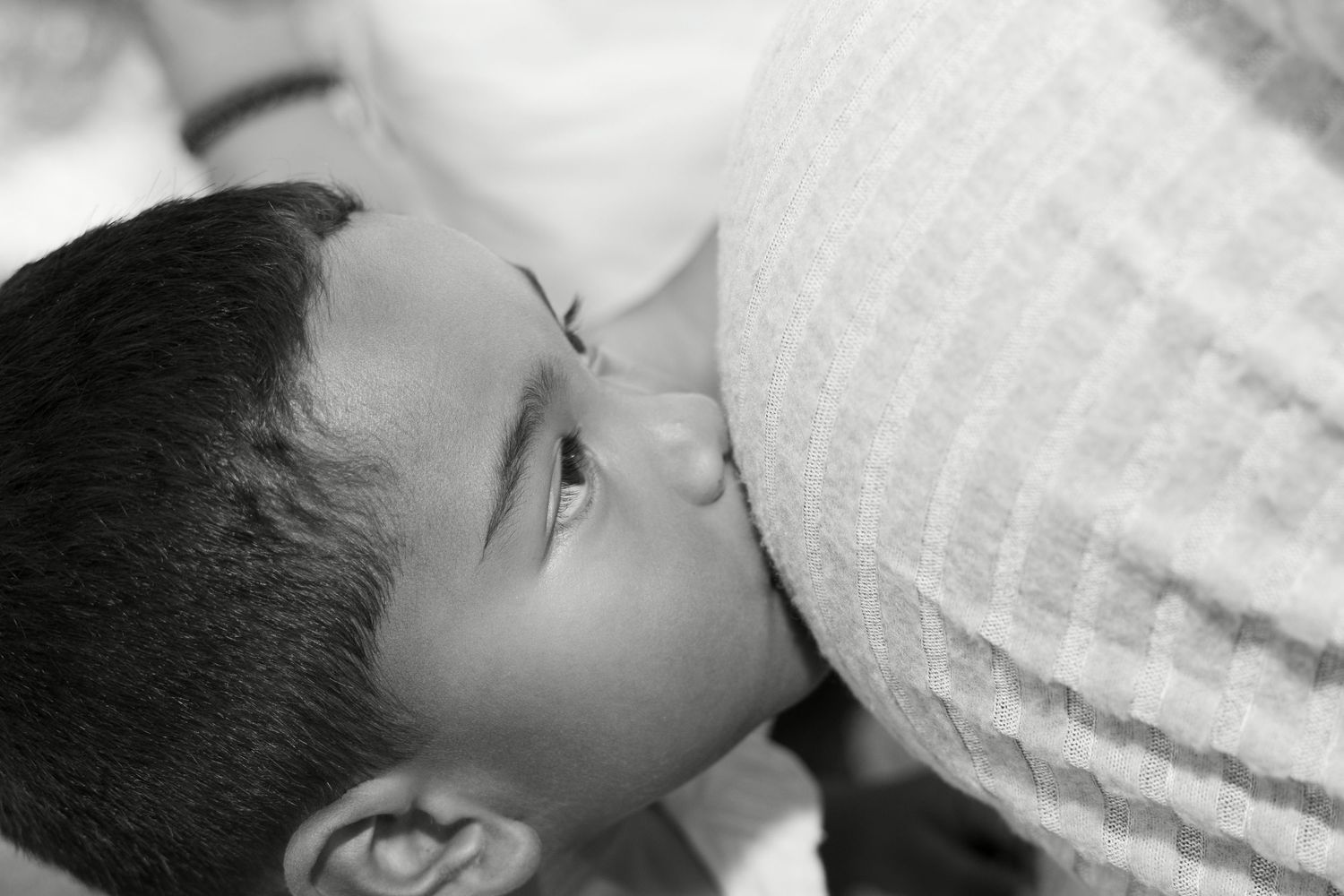 Black and white photo of a baby breastfeeding, close-up portrait.