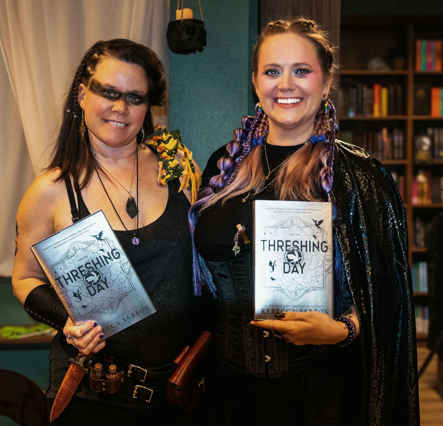 Two women in costumes holding copies of the book Threshing Day at a bookstore event.