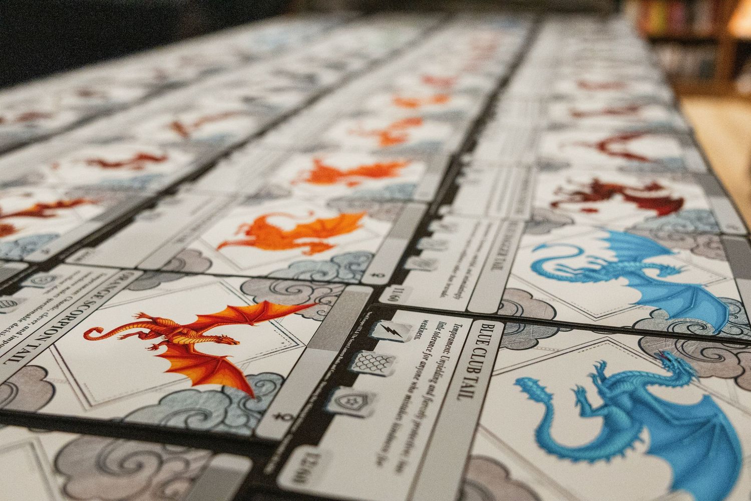 Rows of dragon-themed trading cards featuring red and blue dragon illustrations arranged on a table.