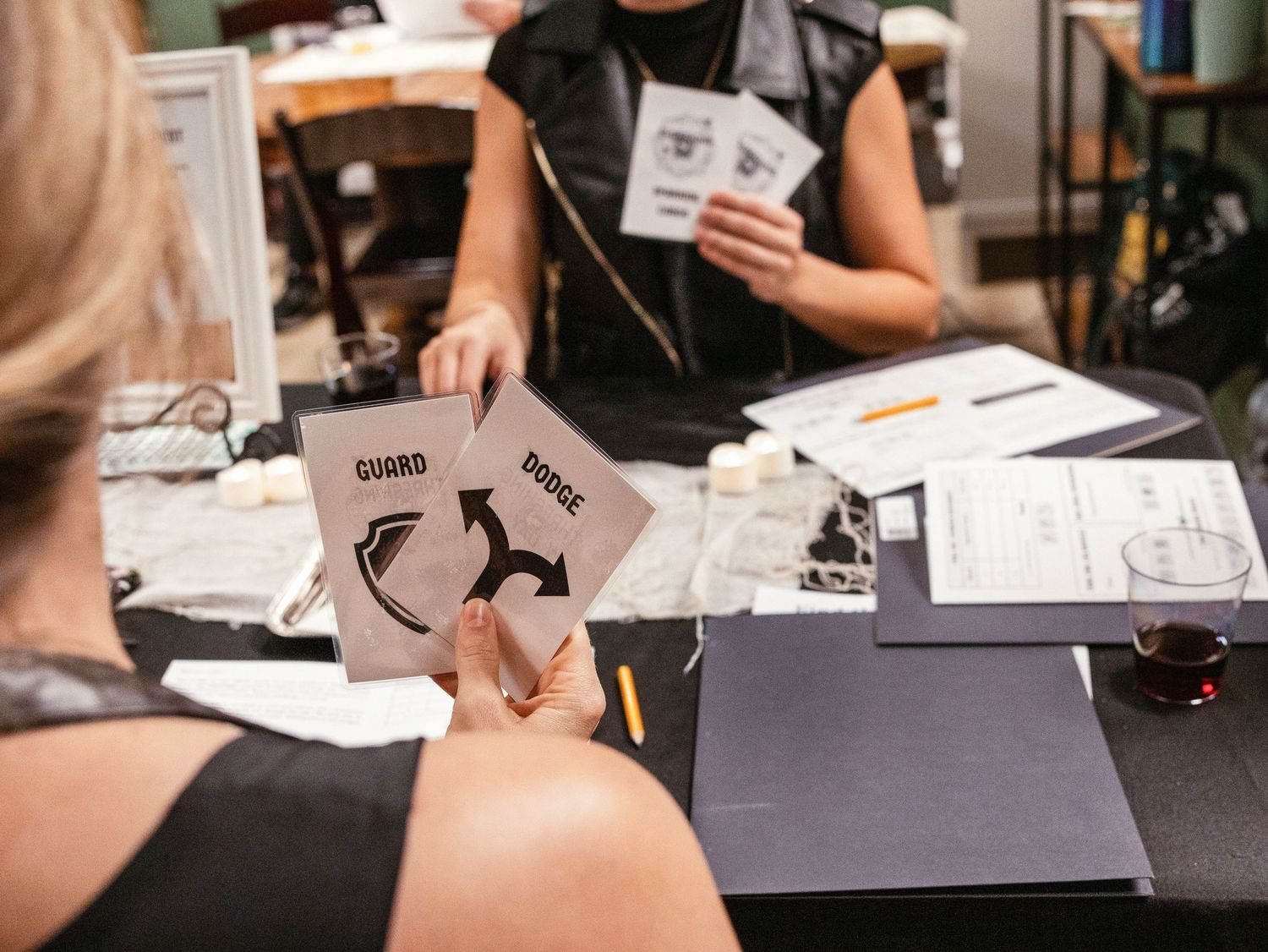 Players hold game cards labeled Guard and Horse during a tabletop role-playing game session at an event.