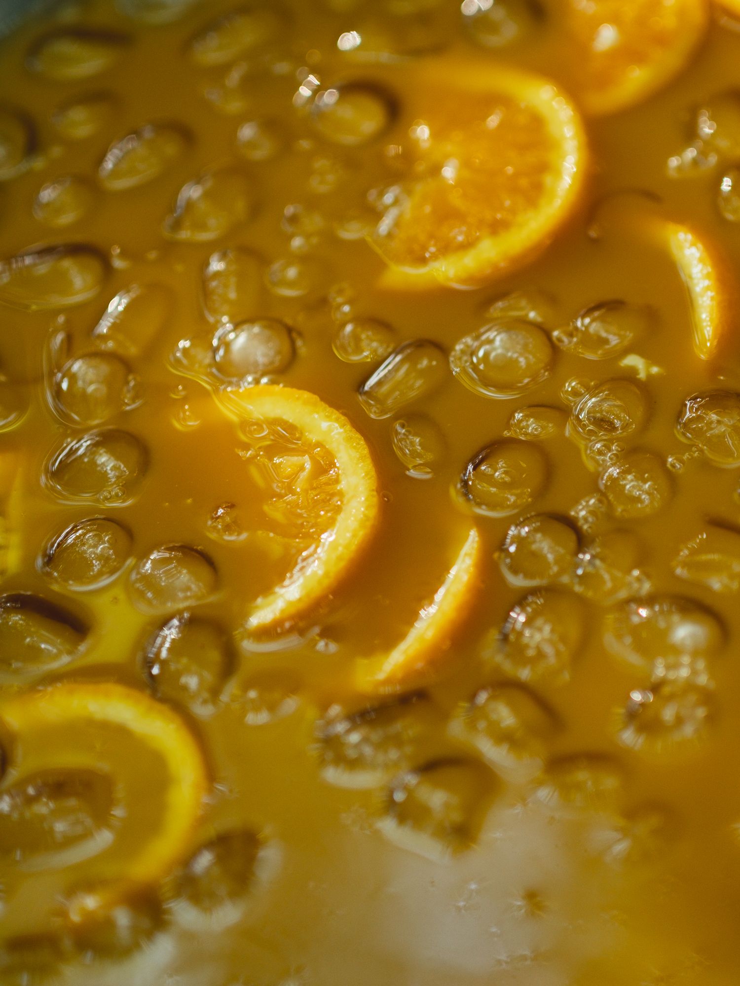 Bubbling orange marmalade with fresh orange slices cooking in a pot of golden syrup.