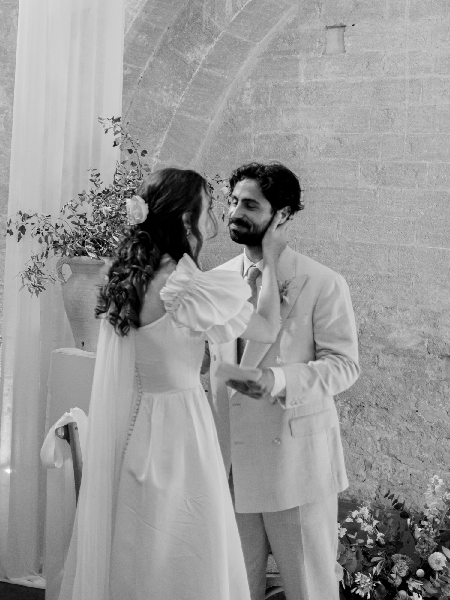 Black and white photo of a bride and groom sharing an intimate moment at their outdoor wedding ceremony.