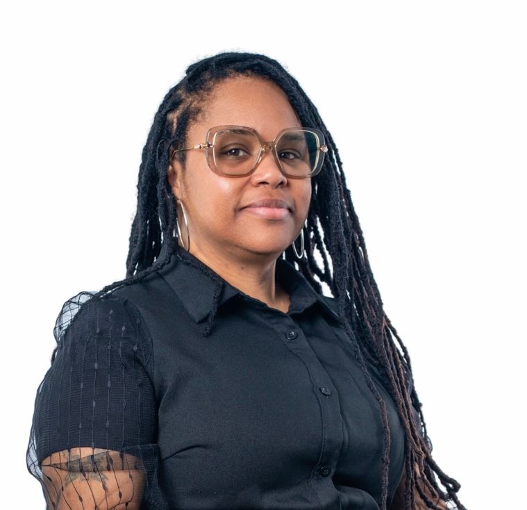 Professional woman with long locs and glasses wearing a black button-up shirt against white background.