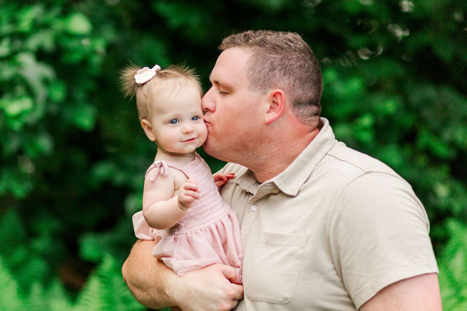 Sweet candid moments captured between parent and infant in a lush green garden setting for a family session in Clemson, SC
