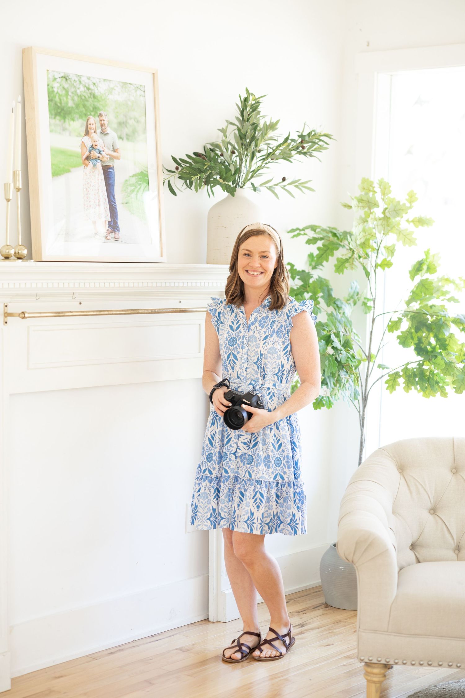 A bright white studio space with soft natural light, indoor plants, and a cozy armchair creates an elegant photography setting.