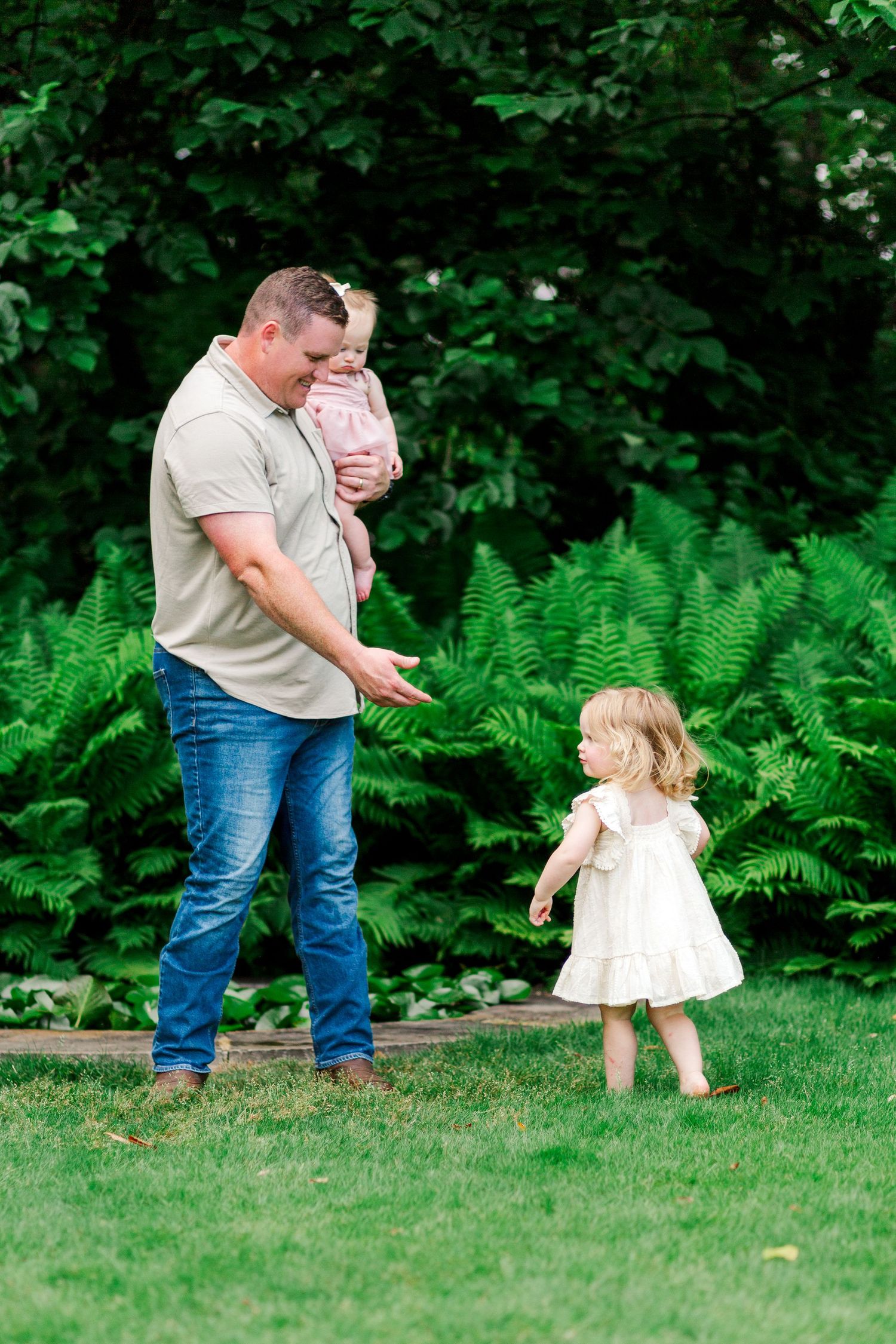 Playful interaction between family members for a photo on grassy lawn surrounded by ferns and greenery in Clemson, SC