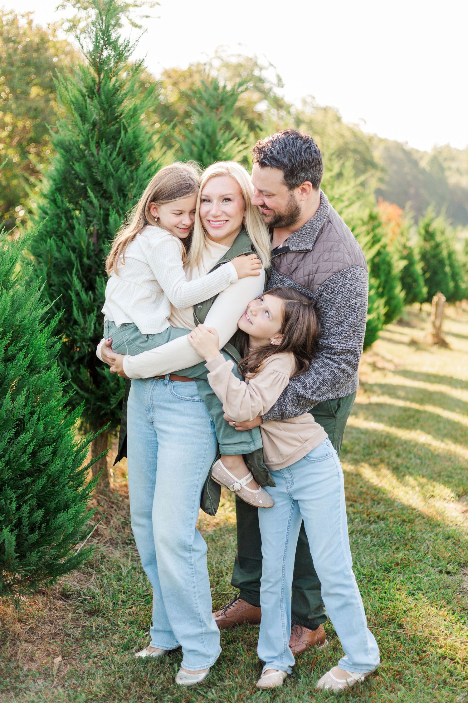 A playful family photoshoot with casual outfits among evergreen trees in Greenville, SC