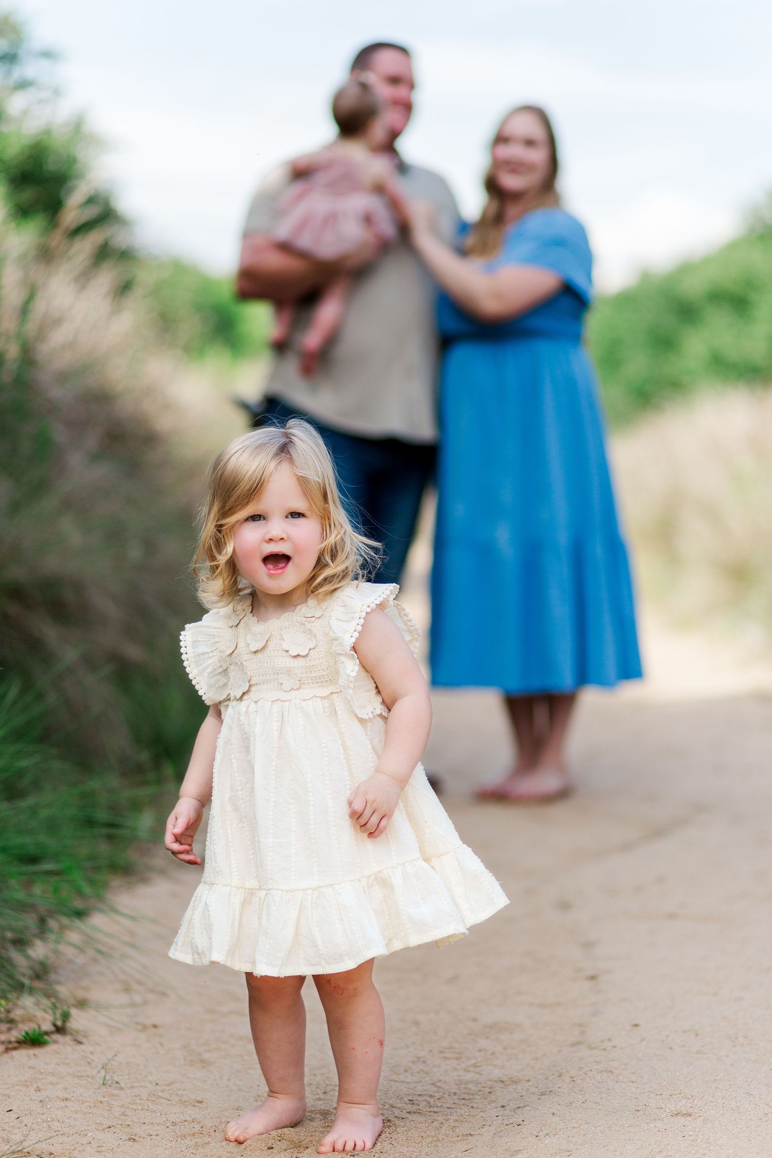 Small child in a white ruffled dress twirls playfully in Clemson, SC for family photo session.