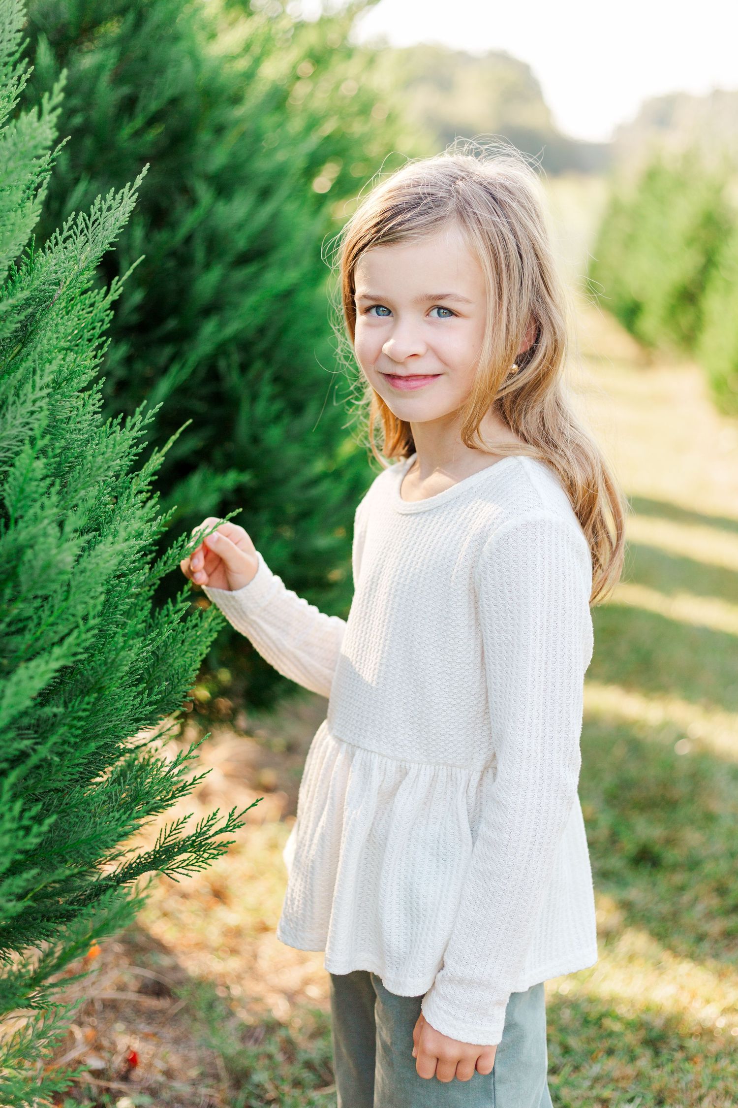 A child in white dress poses playfully for family photo session in Greenville, SC.
