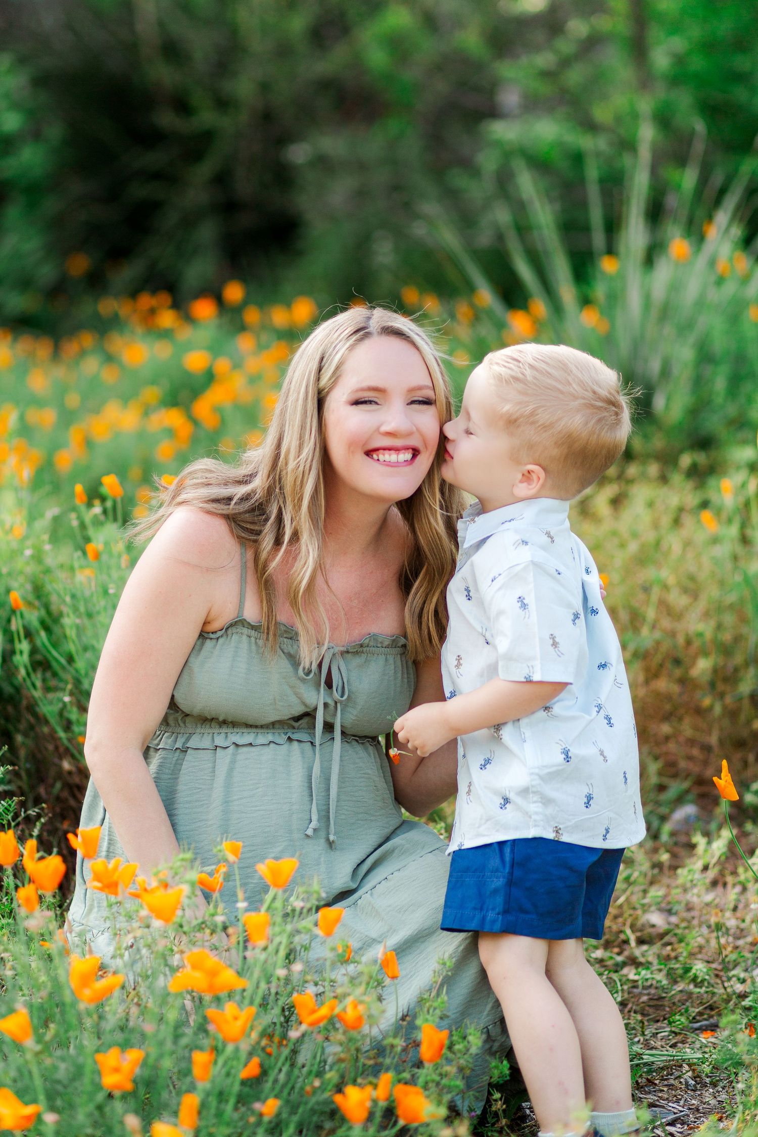 A tender moment shared in a field of vibrant California poppies on a sunny afternoon.