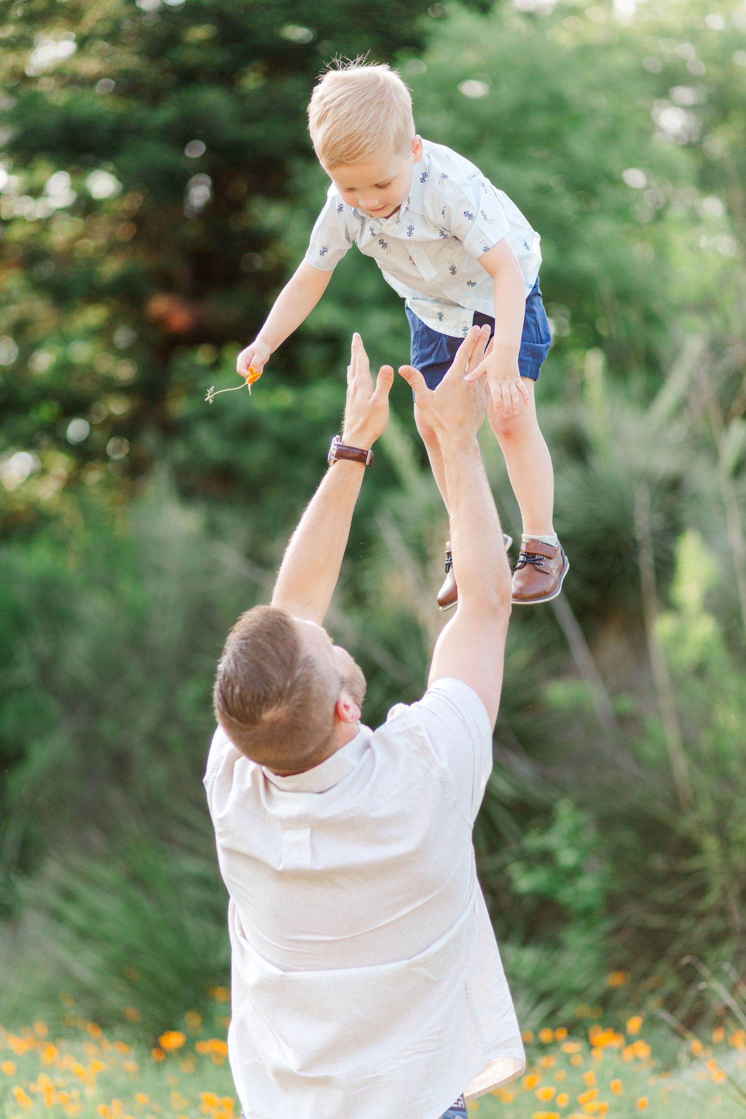 A father plays with a small child during a spring family photo session at the Botanical Gardens in Clemson, SC