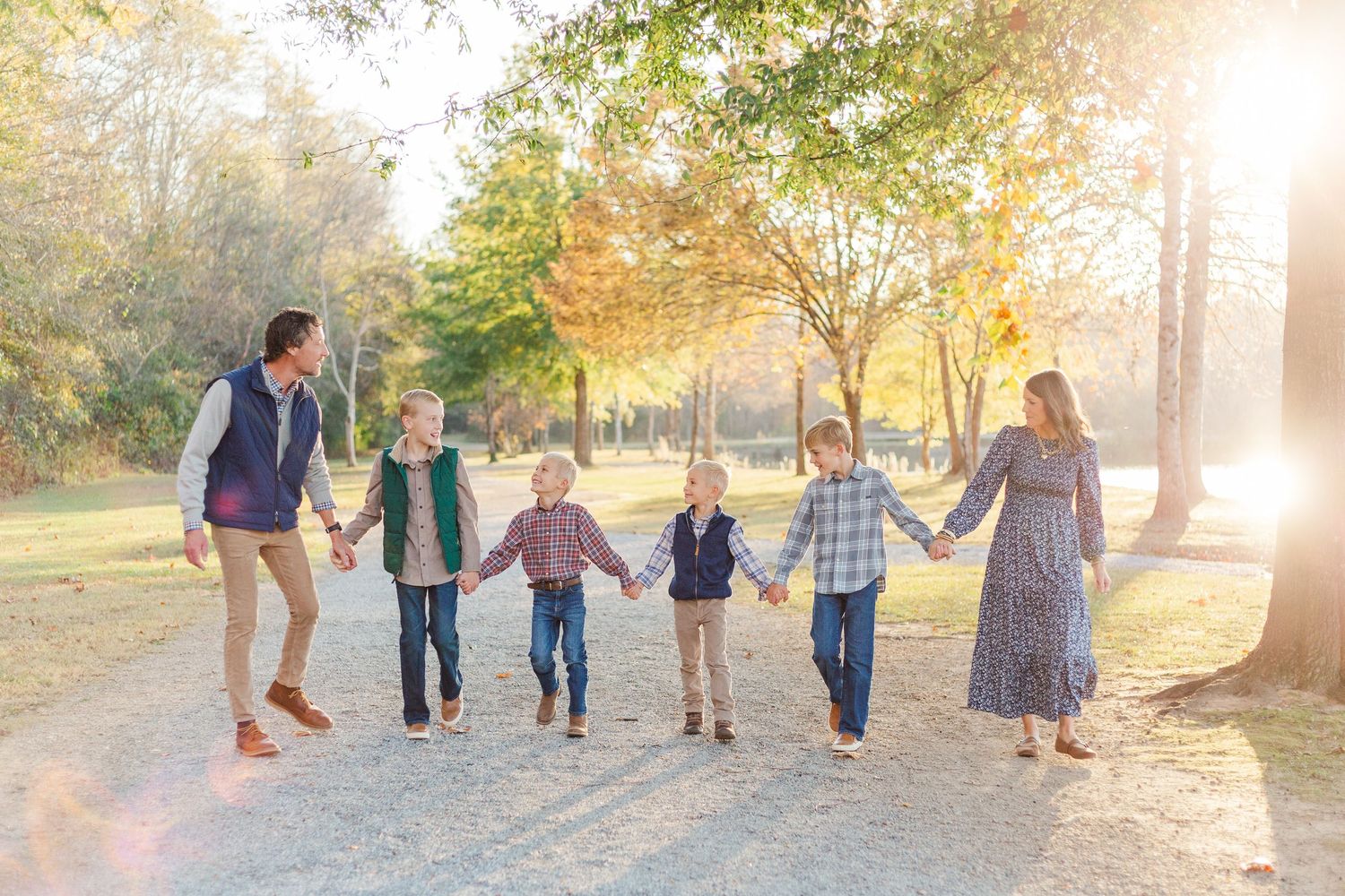 Family walking together on a sunlit autumn path through a park during golden hour.