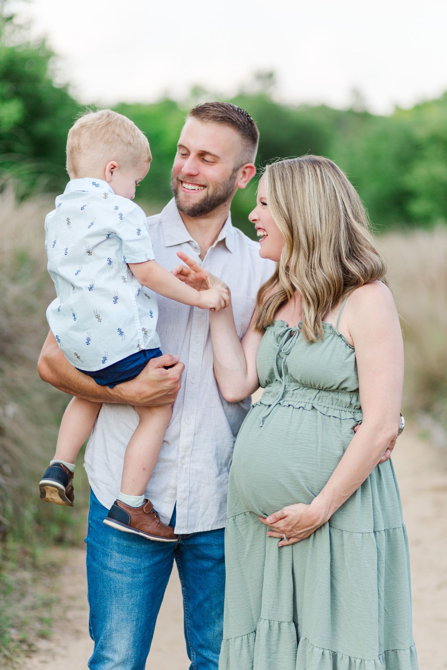 A family in coordinated blue and sage green outfits shares joyful moments together during an outdoor photo session.
