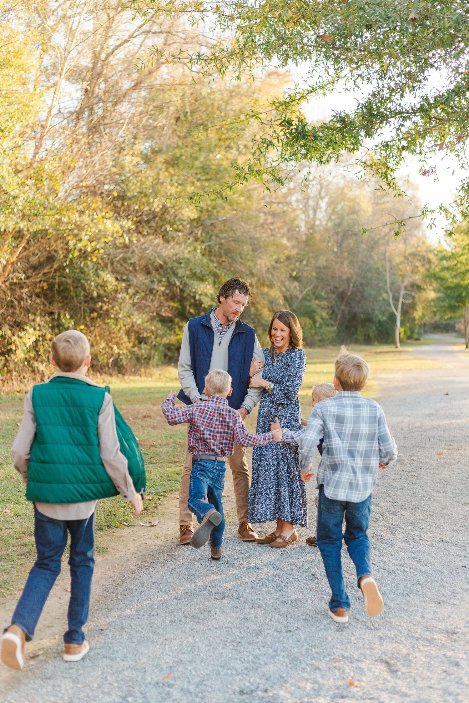 A group walking together on a gravel path through an autumn park setting during golden hour.