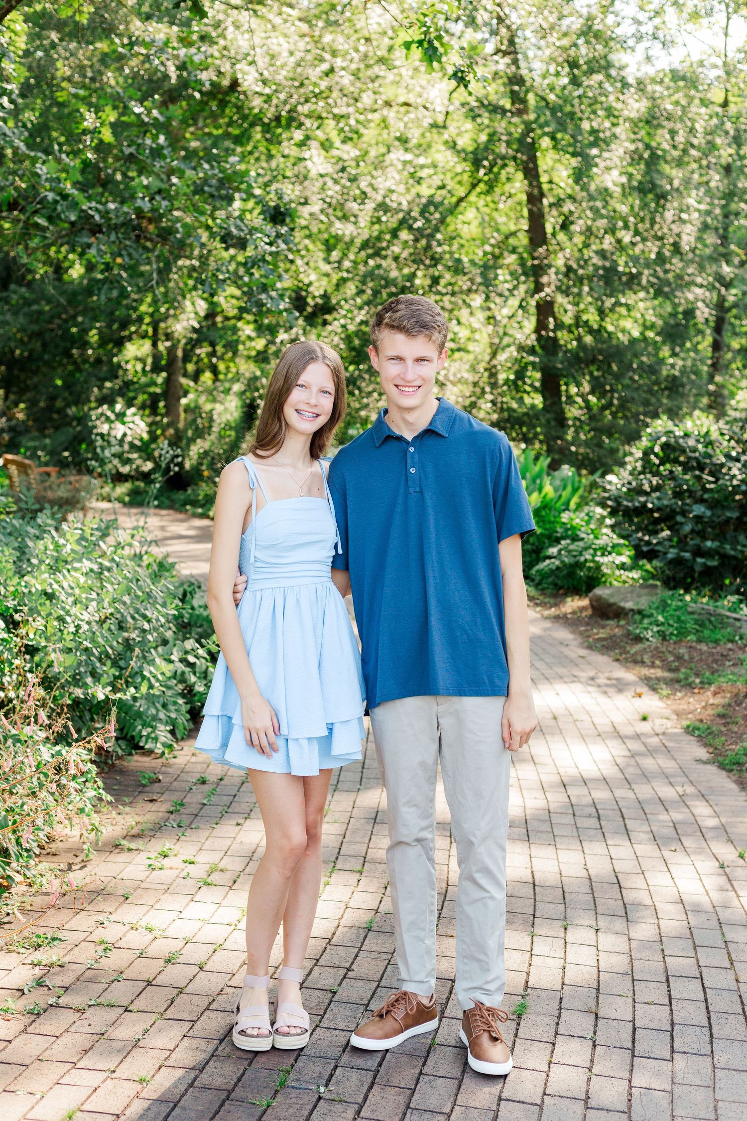 Two high school seniors in coordinating blue and white outfits standing in the Botanical Gardens in Clemson, SC