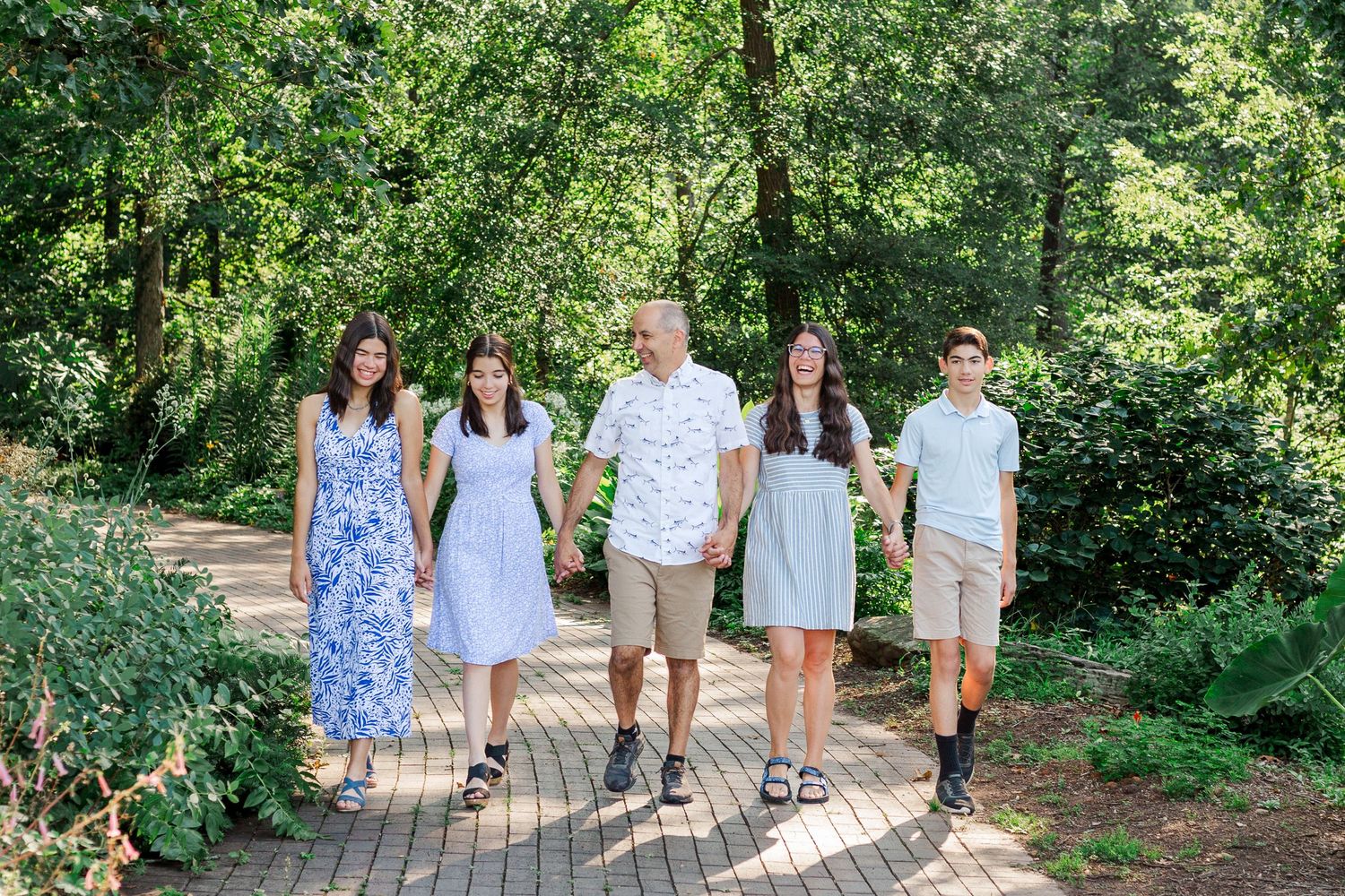 A family photo session walks together at the Botanical Gardens in Clemson, SC