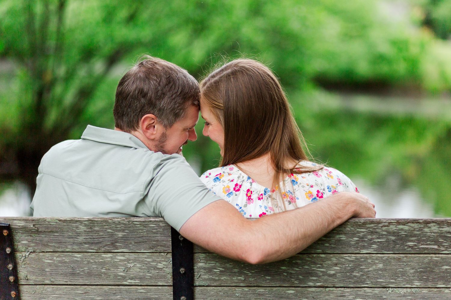 Couple sitting together on wooden bench for a family photo session in Hendersonville, NC taken by a Clemson, SC photographer