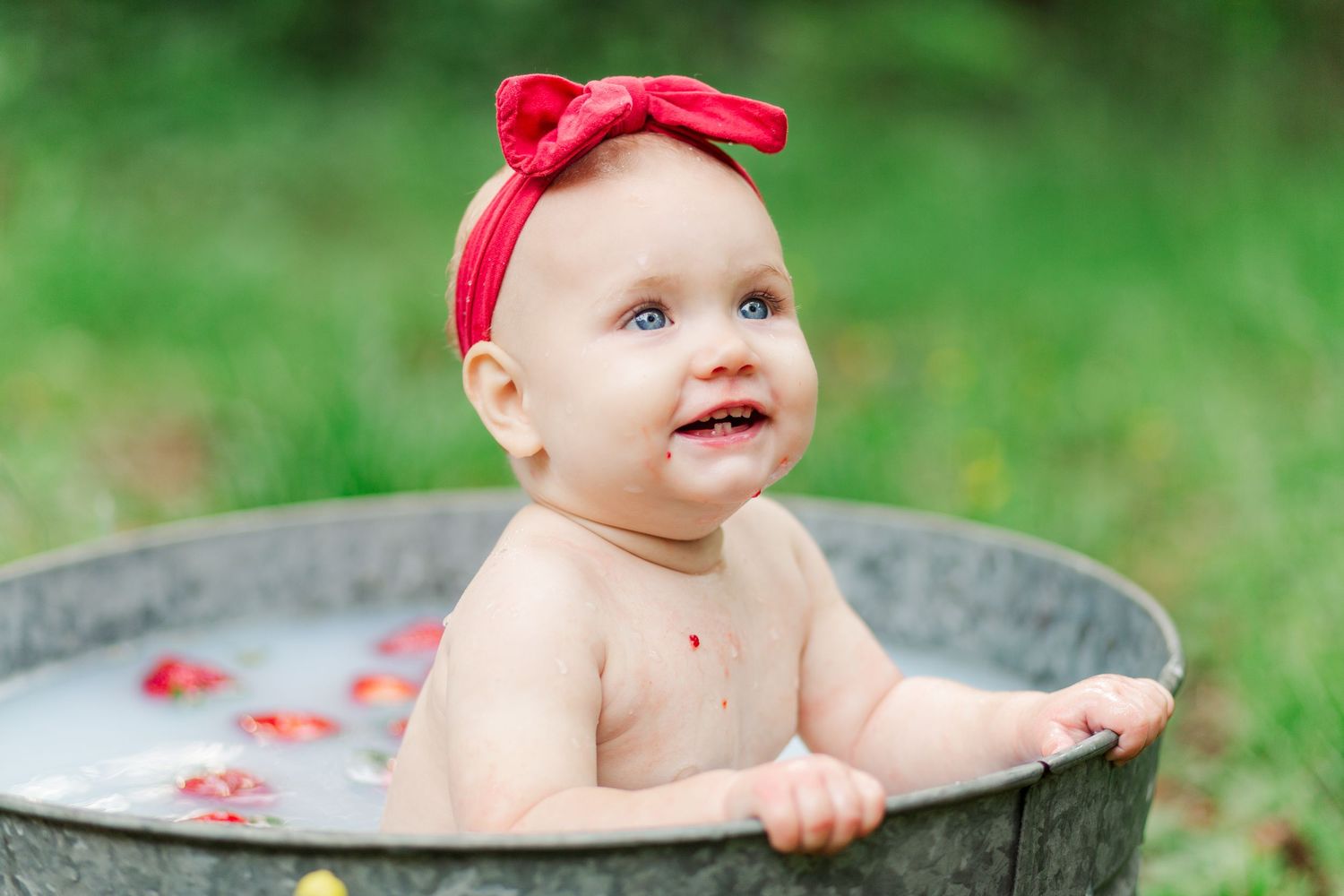 Happy infant wearing red headband sits in Greenville, SC for a birthday session