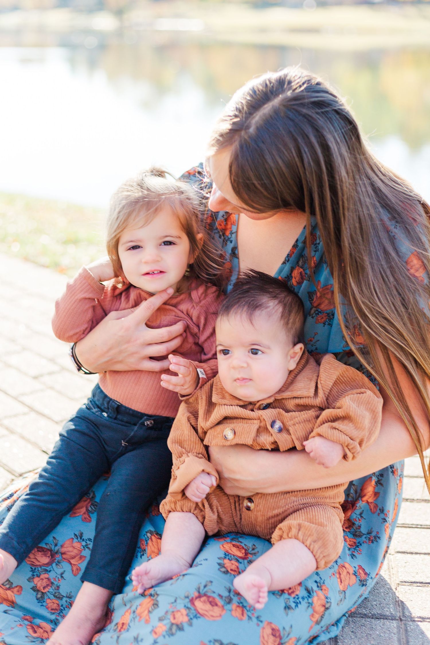 Family sits together outdoors wearing coordinating brown and blue outfits in a tender moment.