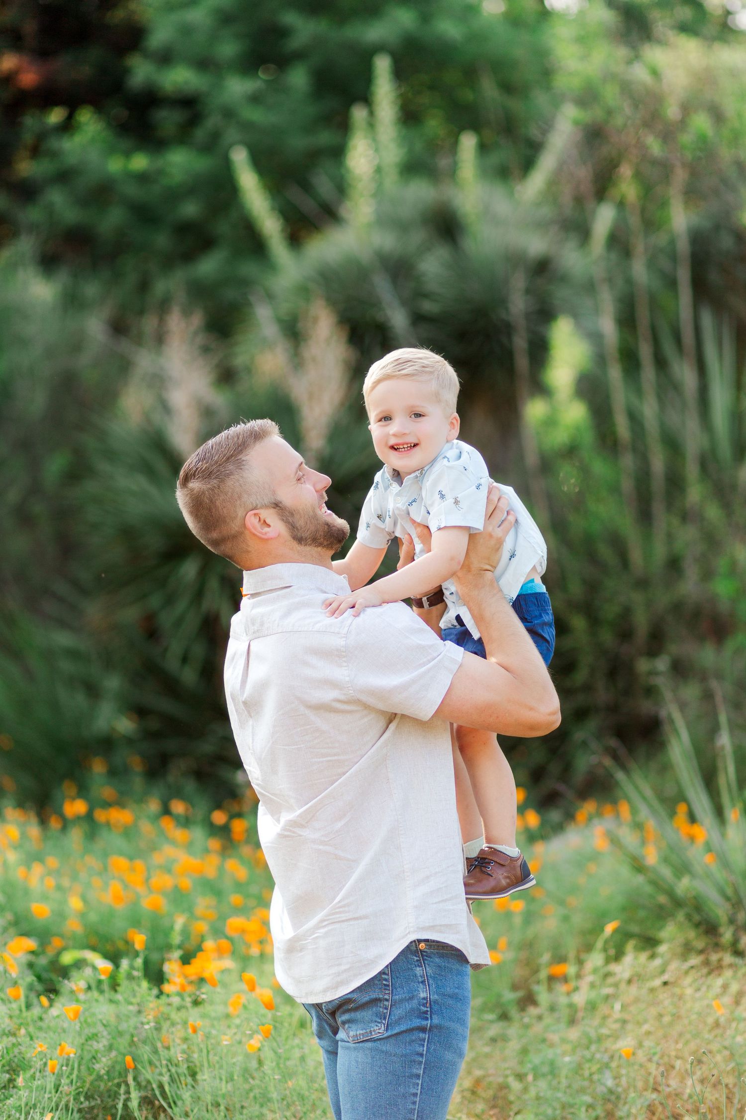 A joyful sequence of a father lifting and playing with his young child in a wildflower meadow during sunset.