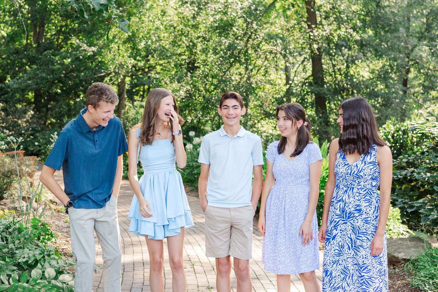A happy group of seniors wearing coordinated blue and white outfits walks along a path at the Botanical Gardens in Clemson, SC