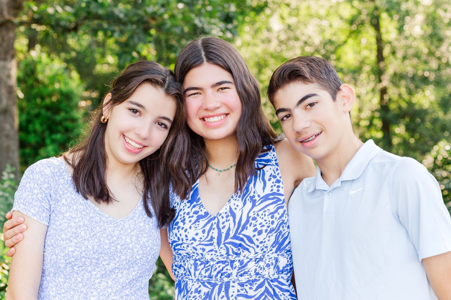 Three high school seniors smiling together outdoors on a sunny day at the Botanical Gardens in Clemson, SC