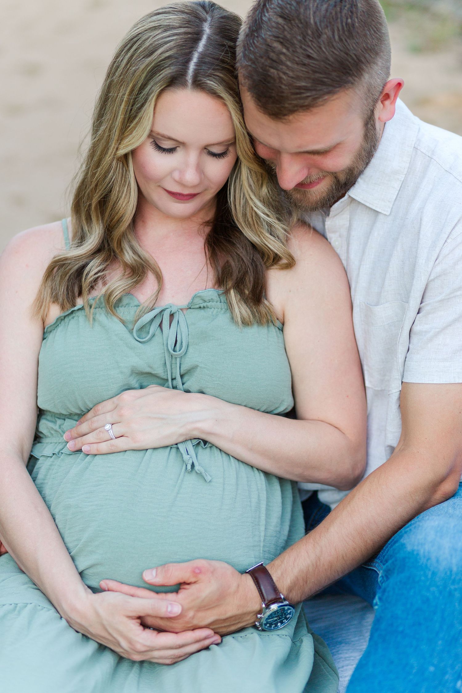 Couple sharing intimate moment during maternity photoshoot wearing mint green dress and white shirt outdoors in Clemson, SC