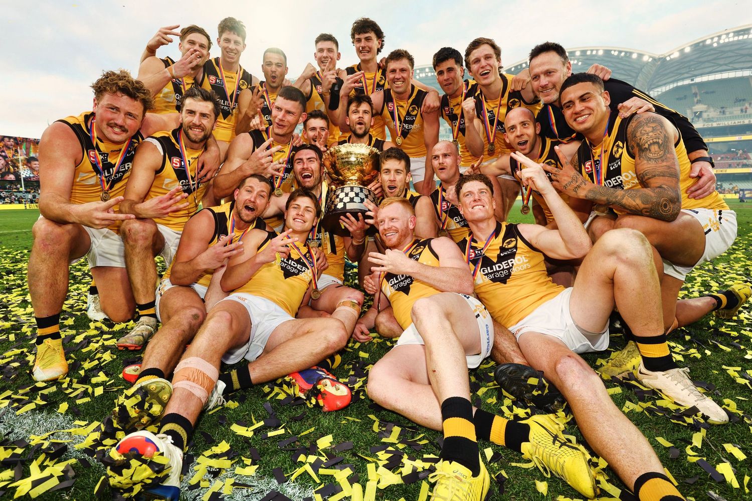 Sports team celebrates championship victory on field covered in yellow confetti.