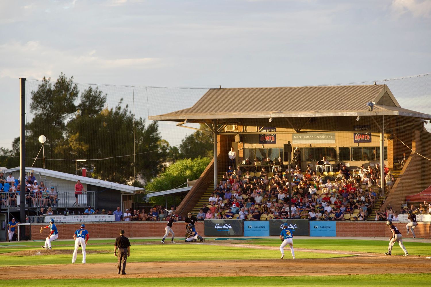 Panoramic view of baseball stadium with crowd watching game during daytime.