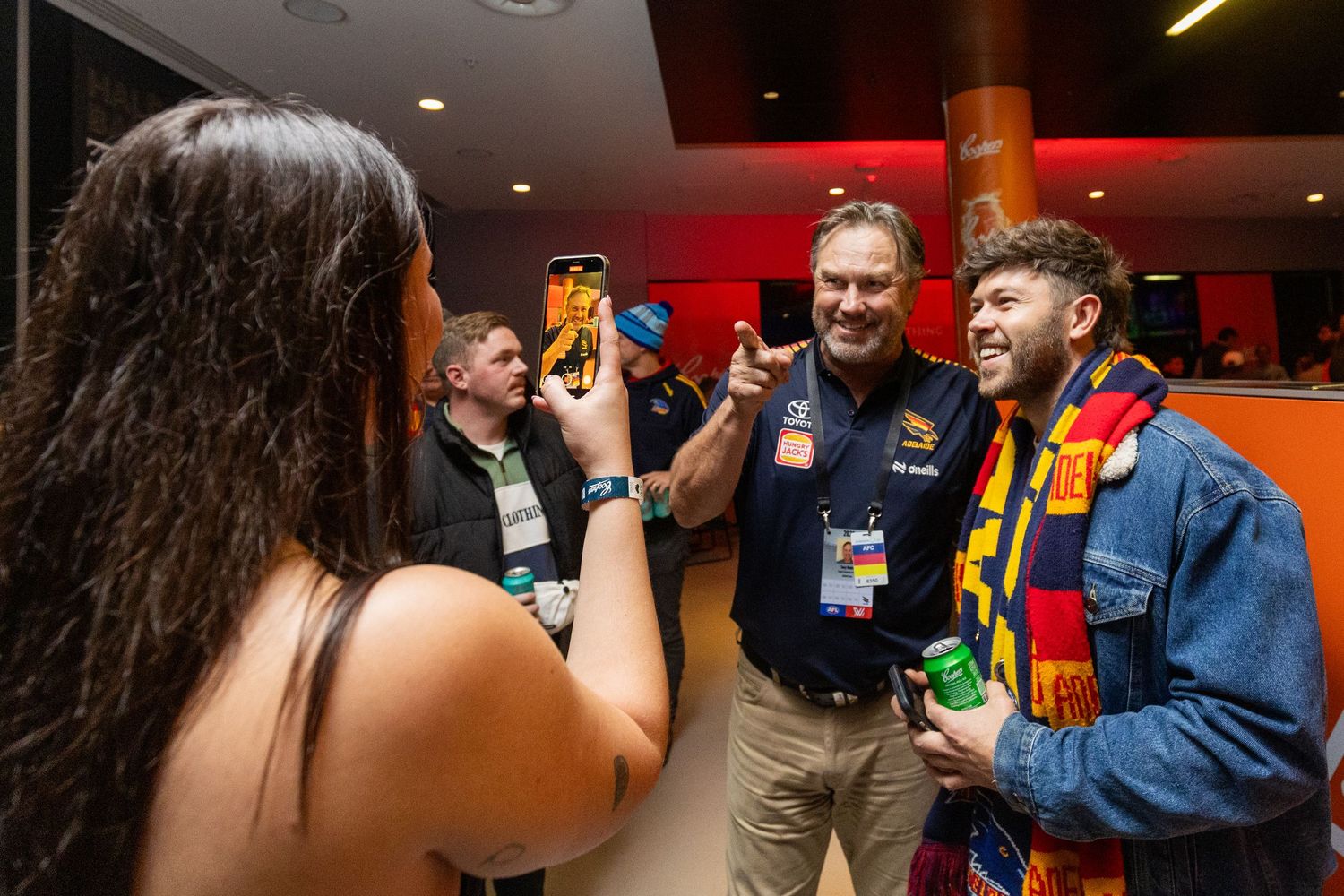 Crowd mingling at an indoor event with orange and red ambient lighting.