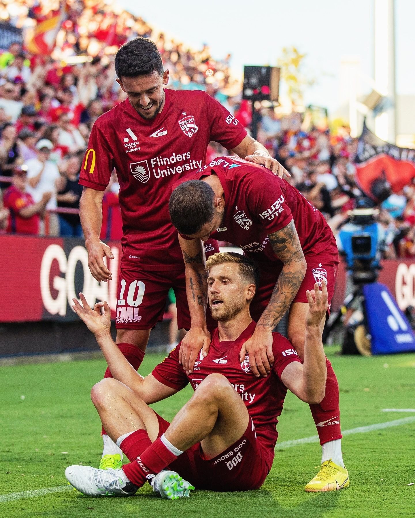 Soccer players celebrate together after scoring goal in red uniforms.