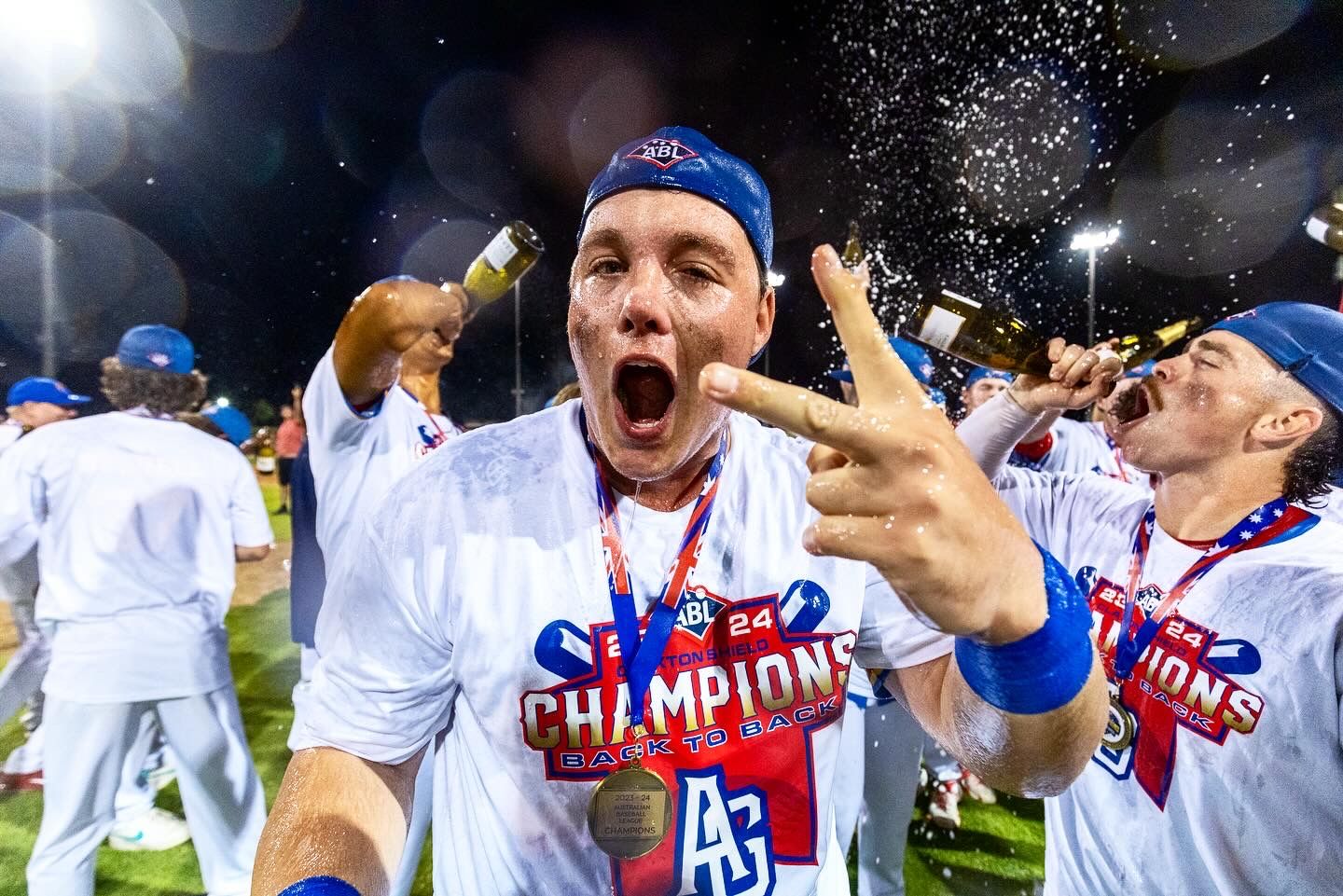 Baseball players celebrate with champagne sprays after winning championship game.