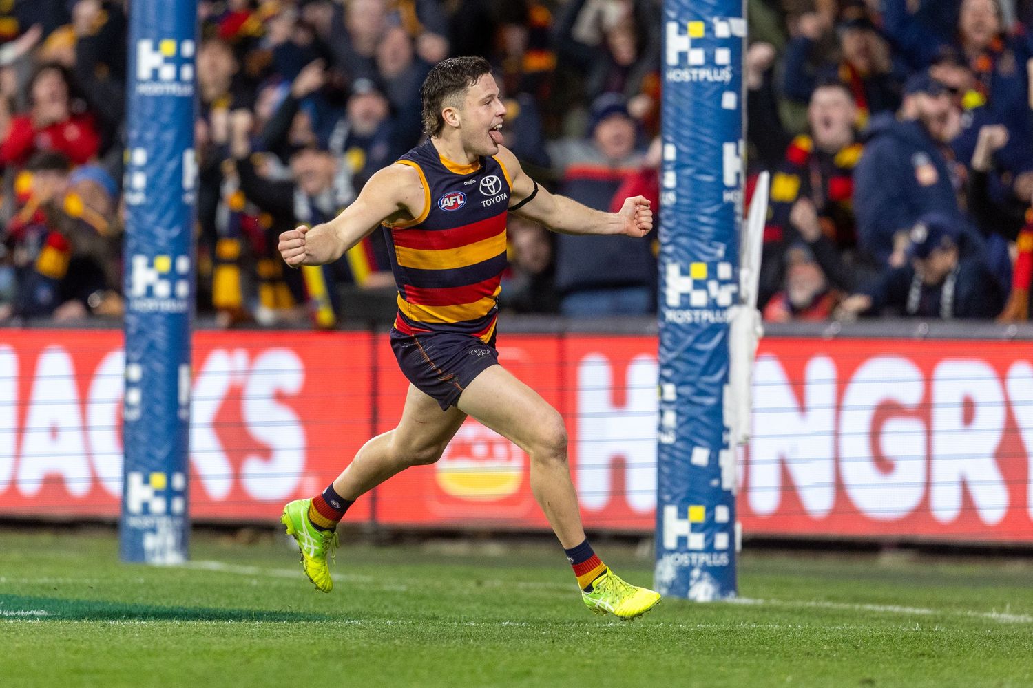 AFL players diving for ball during competitive match at stadium.