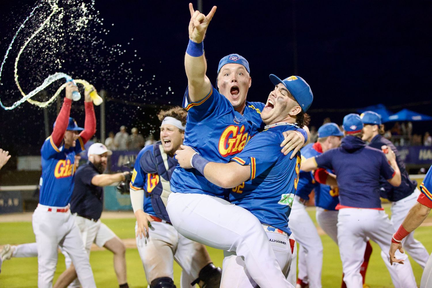 Baseball team celebrates victory with energetic celebrations under stadium lights.