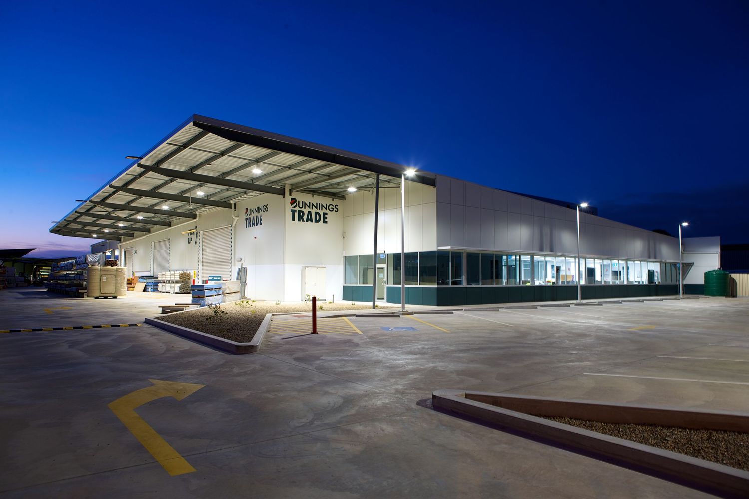 Modern industrial warehouse exterior with loading bays at night under blue lighting.